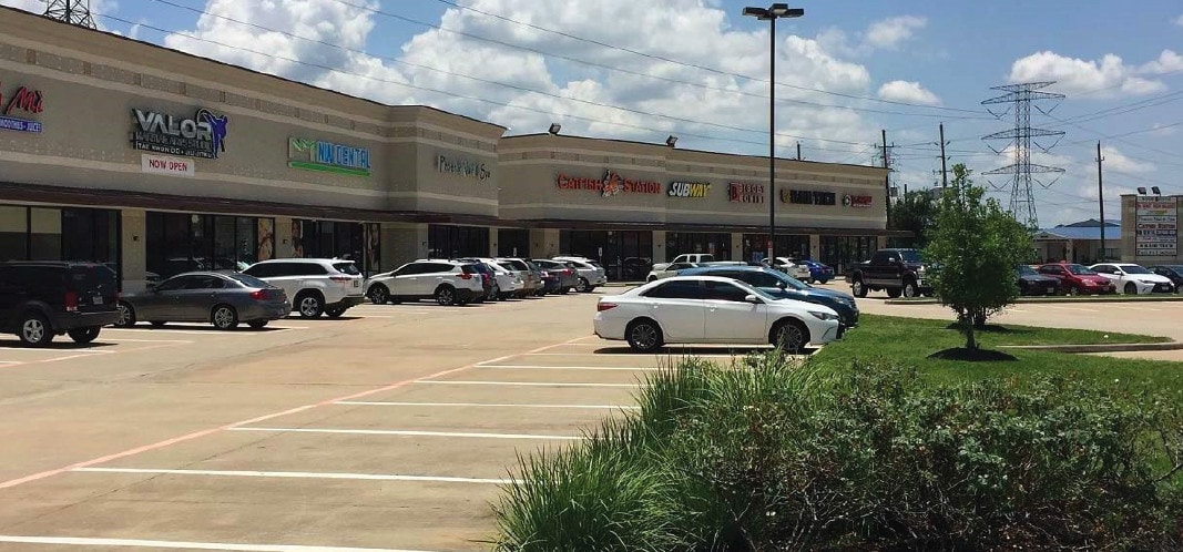 Wide view of the retail center parking lot and tenant storefronts