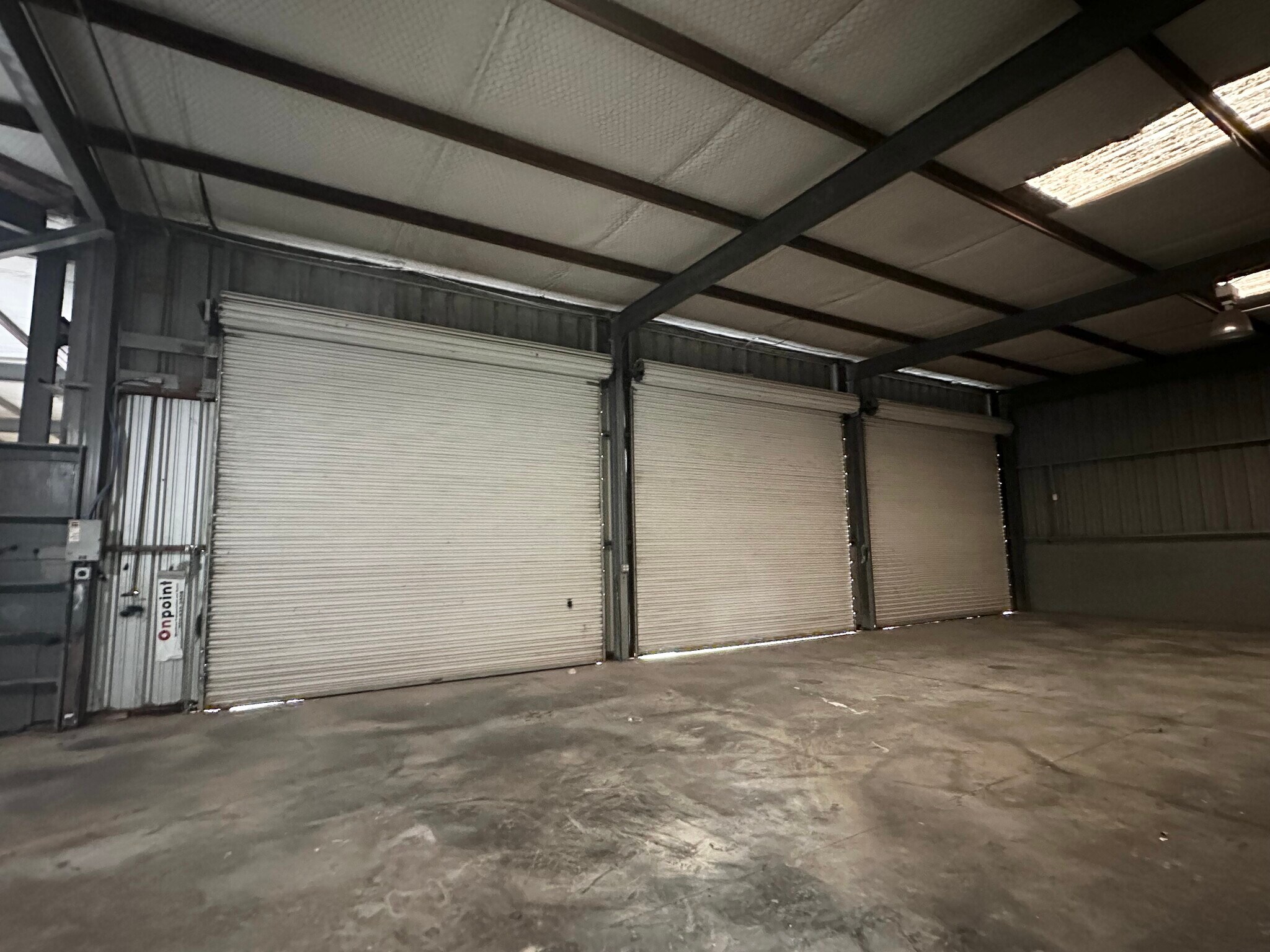 Secondary warehouse interior with three roll-up doors at 13626 Ann Louise Rd