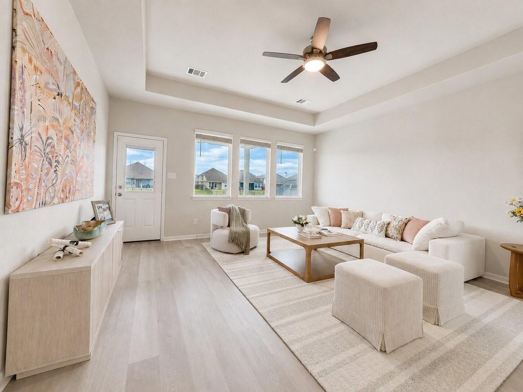Living room with tray ceiling and backyard windows