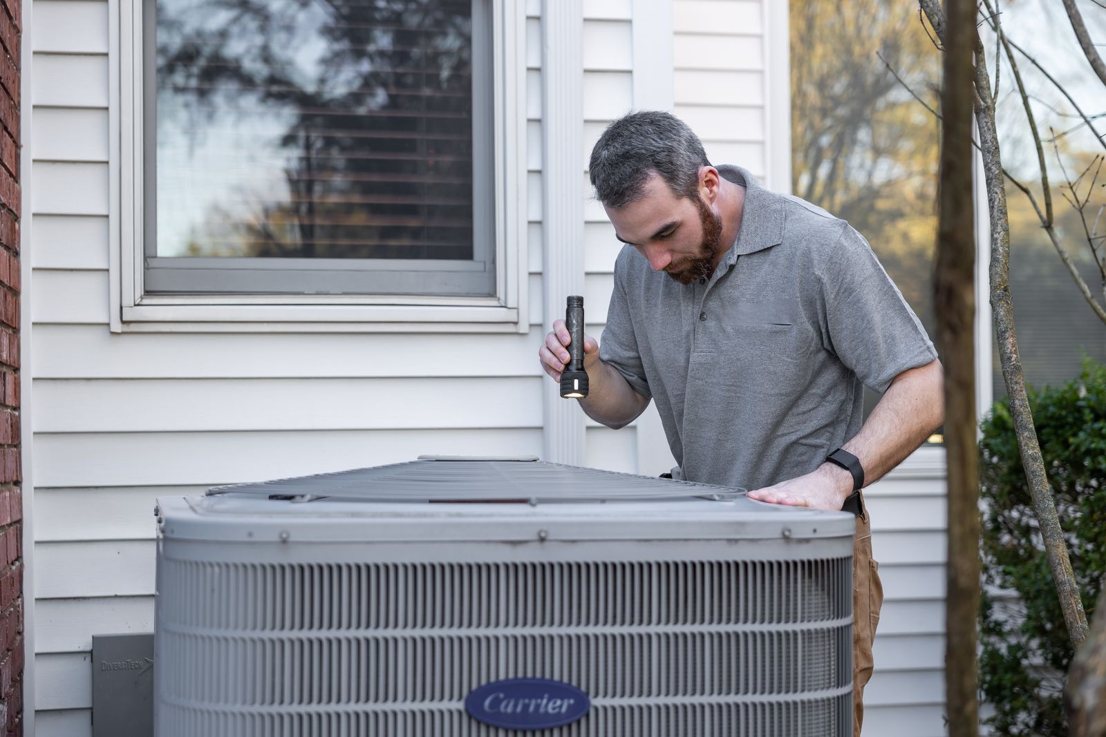 Technician inspecting a residential outdoor HVAC unit / 技术人员检查住宅室外HVAC空调机组