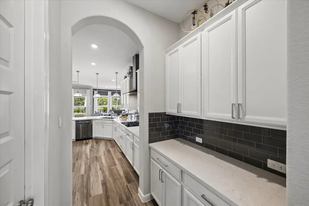 Butler pantry with white cabinetry and dark tile backsplash | 带白色橱柜和深色后挡板的管家备餐区