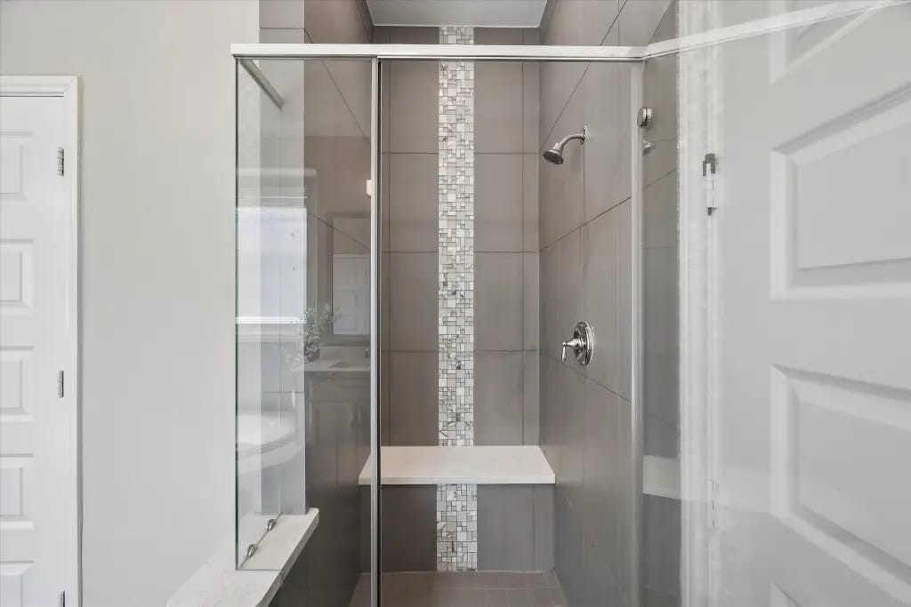Glass-enclosed walk-in shower with bench in the primary bathroom | 主卫带座椅的玻璃步入式淋浴