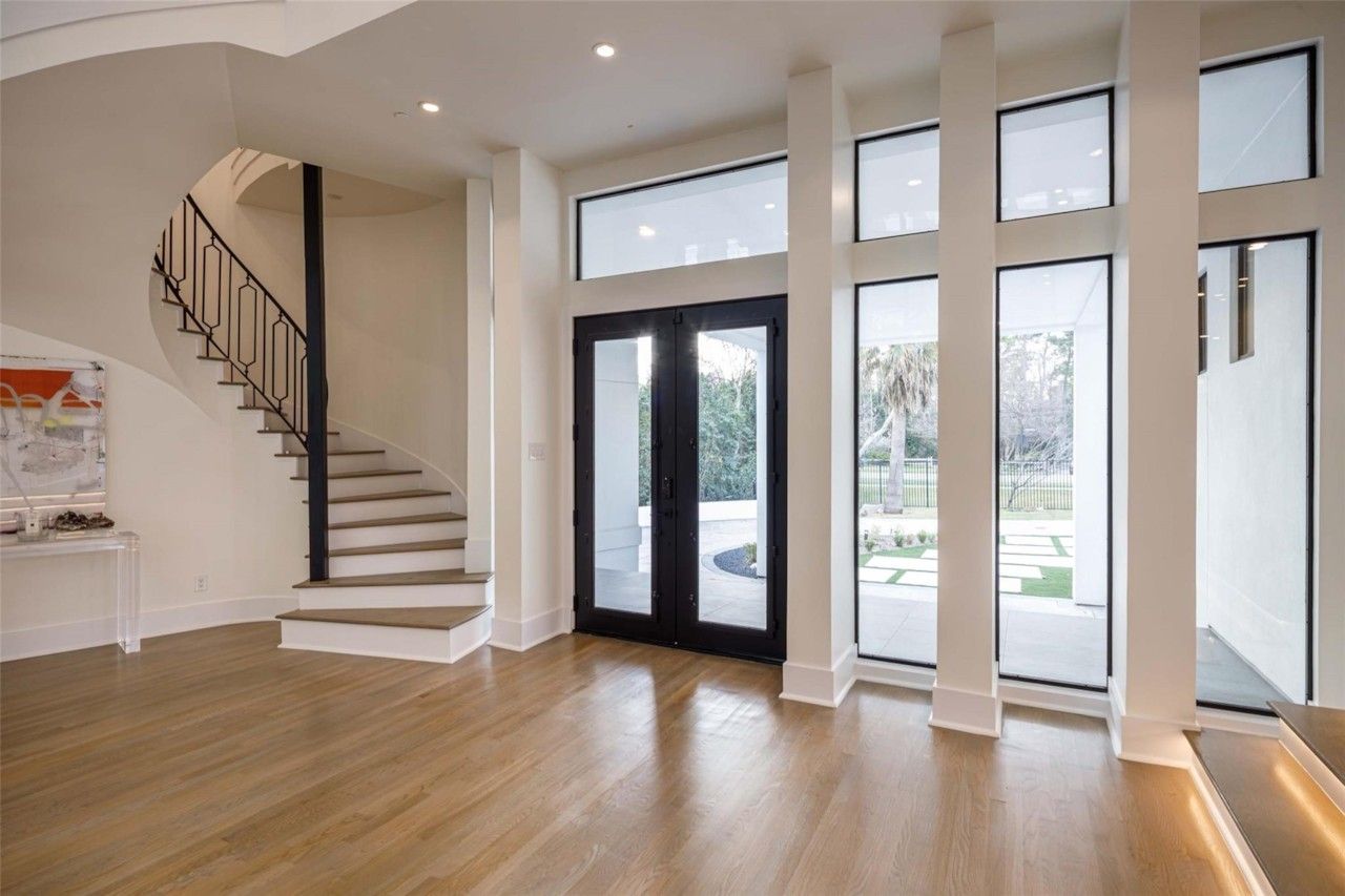 Double-height entry with modern staircase and tall windows