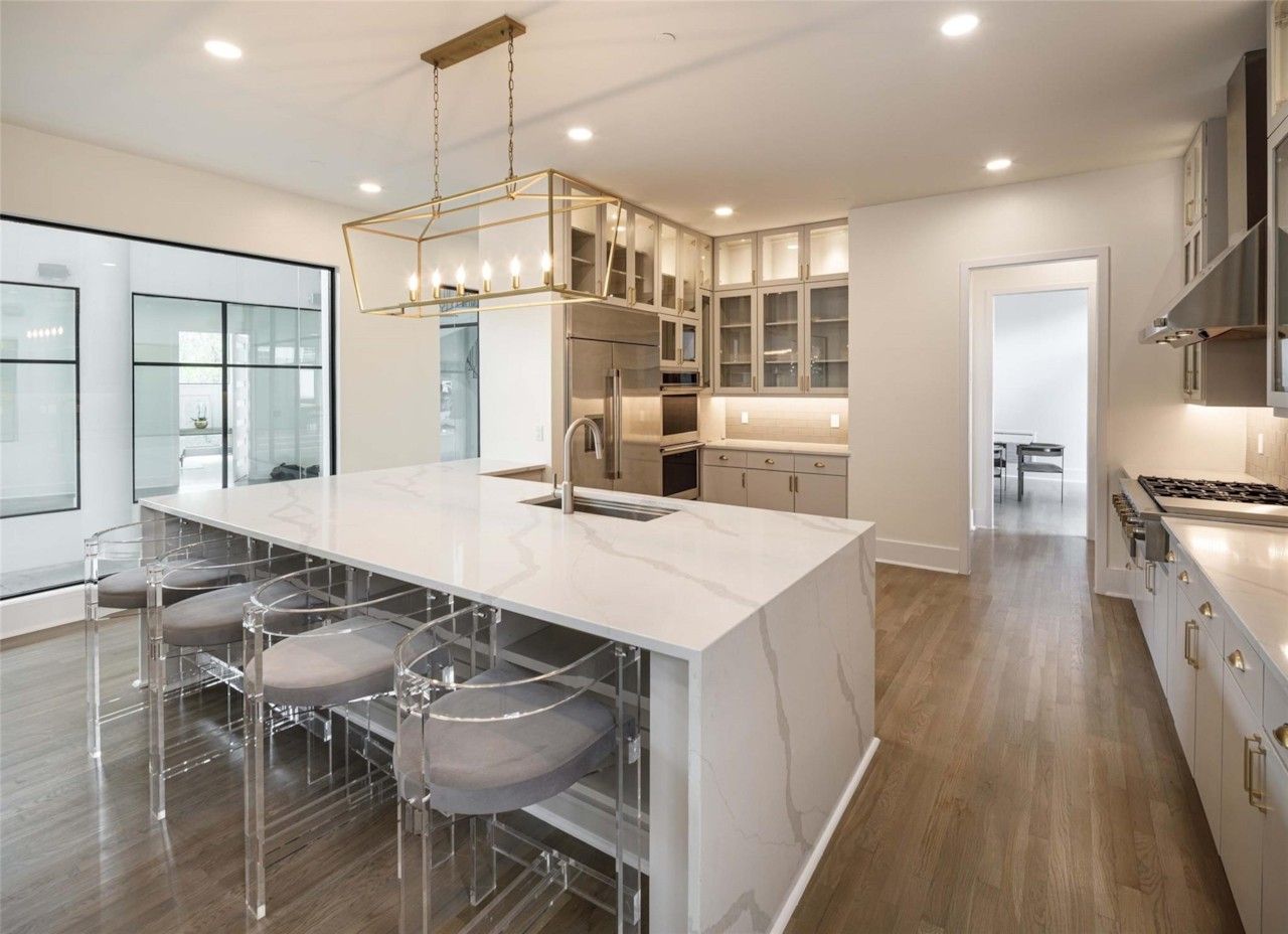 Renovated kitchen with large marble island and white cabinetry