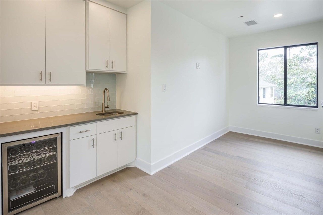 Wet bar with beverage refrigerator and white cabinetry