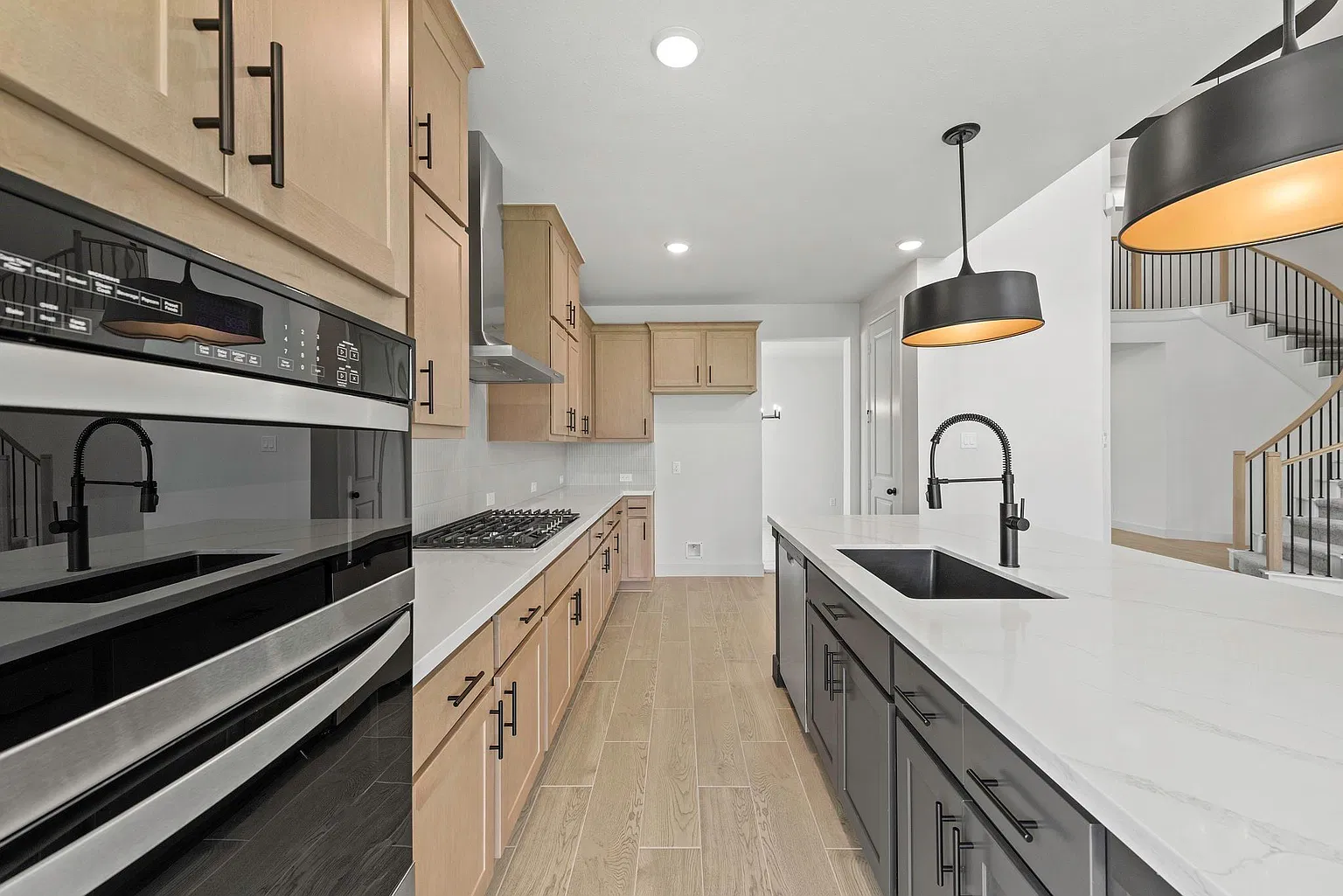 Kitchen work aisle with gas cooktop, wall ovens and island sink | 配燃气炉头、嵌入式烤箱和岛台水槽的厨房操作区