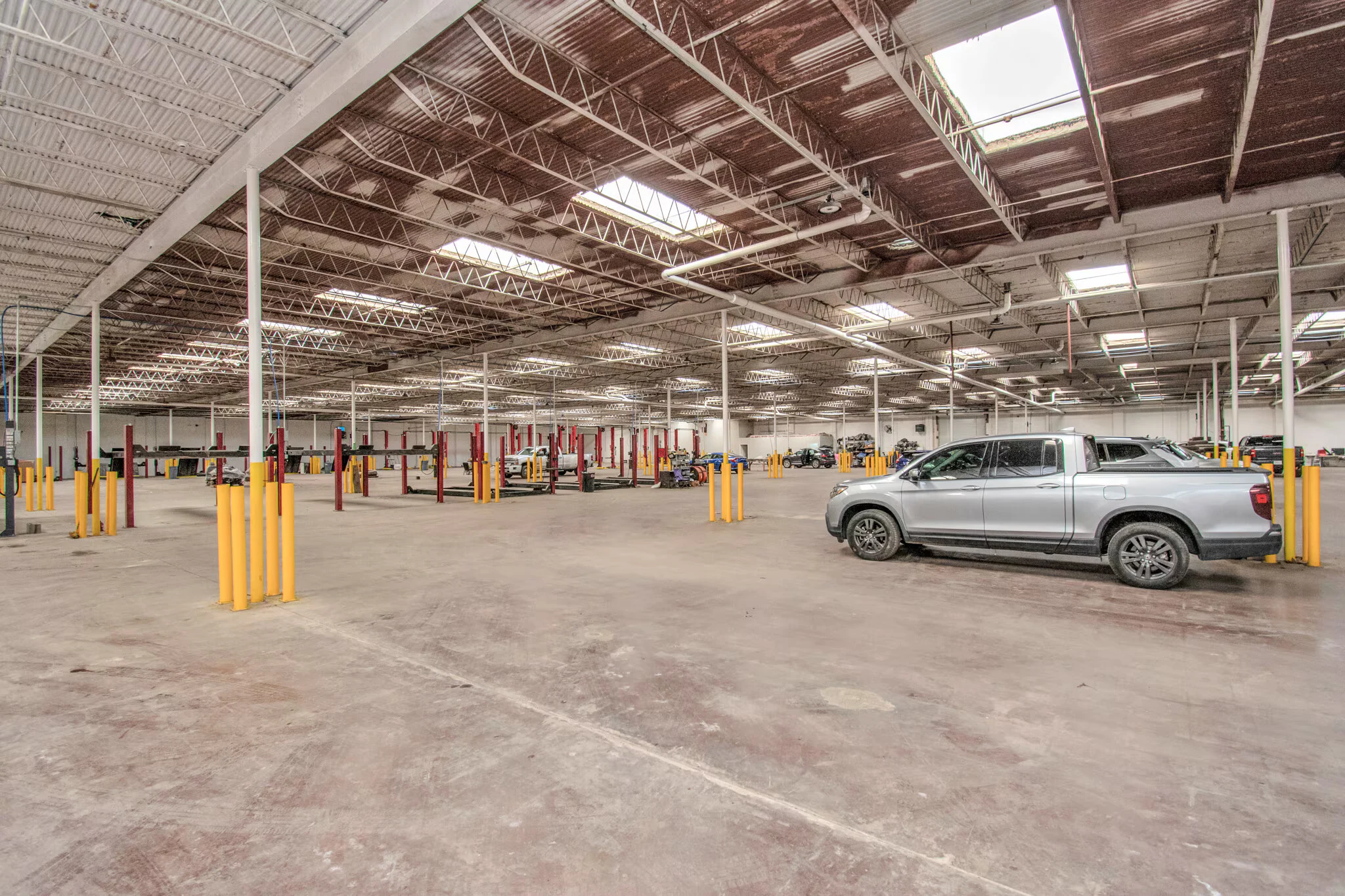Wide warehouse interior showing open floor area, columns and skylights | 展示开放地面、立柱和天窗的仓库内部广角
