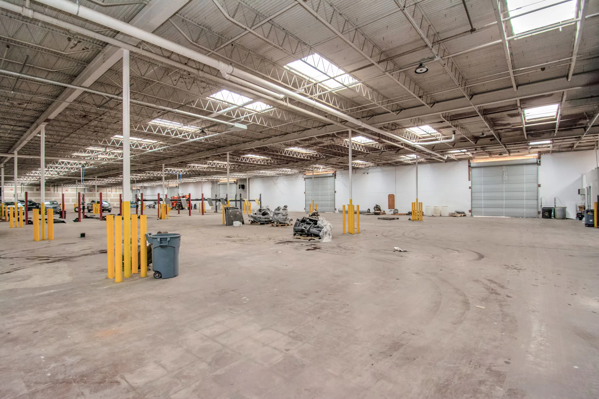 Open warehouse area with skylights, columns and a large drive-in door | 带天窗、立柱及大型卷门的开放仓库区域
