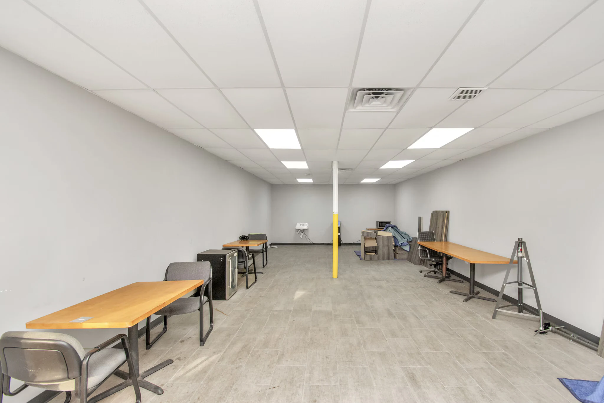 Open office or workroom with tables, hard-surface flooring and overhead lights | 带桌子、硬质地面和顶灯的开放办公或工作间