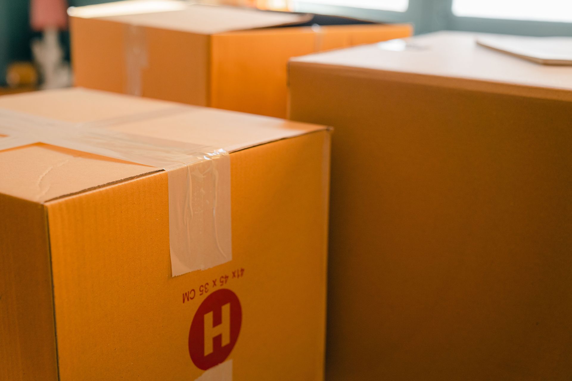 阳光下住宅内已打包的搬家纸箱,象征因人生计划改变而出售房屋 / Packed moving boxes in a sunlit home, representing a sale prompted by a life-plan change