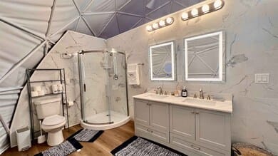 Bathroom inside a geodesic dome with glass shower and double vanity | 穹顶屋内带玻璃淋浴房和双台盆的卫生间